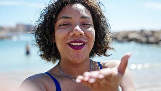 Young beautiful latin woman tourist having video call blowing kiss at beach