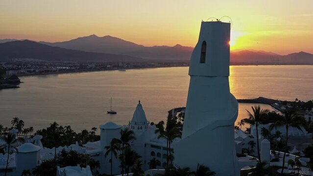 Vuelo de drone en atardecer sobre la ba&iacute;ha de Manzanillo con una torre en primer plano.