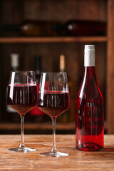 Bottle and glasses of red wine on table in cellar