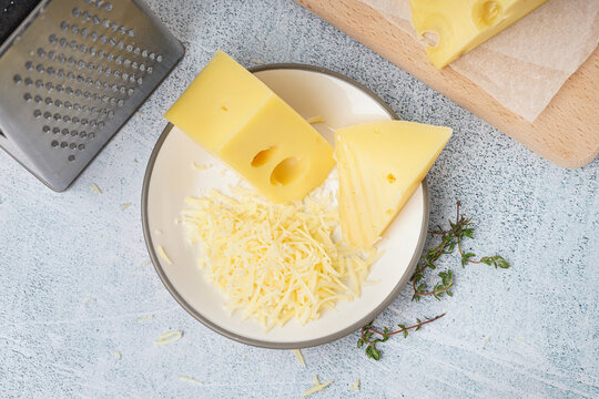 Plate and board with pieces of Swiss cheese on white table