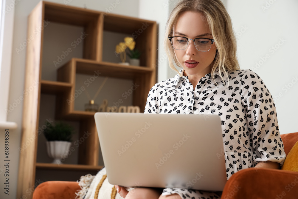 Poster young woman in stylish eyeglasses using laptop at home