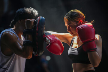 Muay Thai, female boxers practicing punching with a male trainer at a gym in Chiang Mai, Thailand