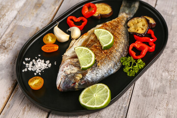 Tray with tasty grilled dorado fish on grey wooden background