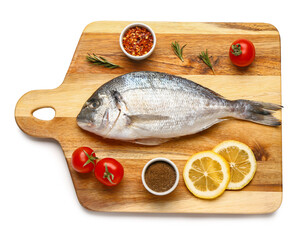 Wooden board of raw dorado fish with lemon and tomatoes on white background