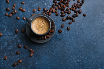 Cup of hot espresso and coffee beans on blue background