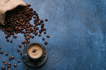 Cup of hot espresso and sack bag with coffee beans on blue background