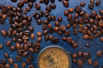 Cup of hot espresso and coffee beans on blue background