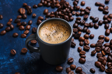 Cup of hot espresso and coffee beans on blue background