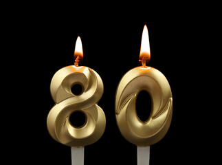 Burning gold birthday candles isolated on black background. Number 80.