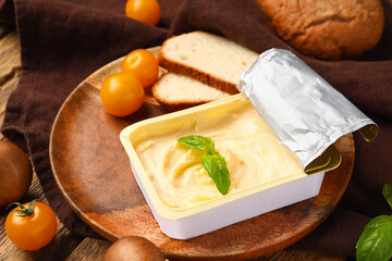 Plastic container with tasty cream cheese, tomatoes and bread on wooden background