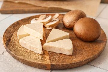 Plate with triangles of tasty processed cheese and mushrooms on light background, closeup