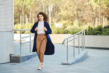 A woman in a hurry leaves the house and throws a coat over her shoulders