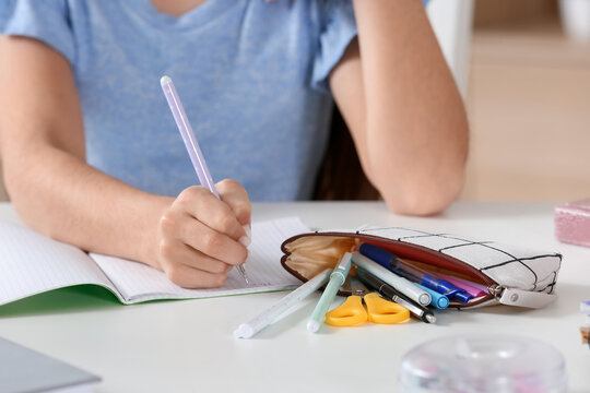 Little girl with pencil case writing at table, closeup - Powered by Adobe