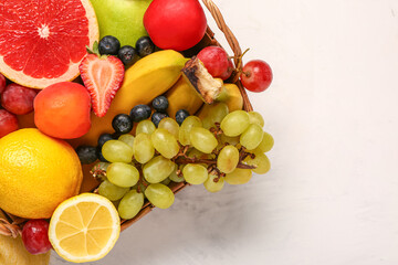 Wicker basket with different fresh fruits on white background