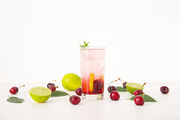 Glass of tasty cherry lemonade with lime and mint on white background