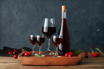 Glasses and bottle with sweet cherry liqueur on wooden table