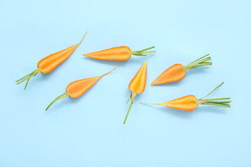 Fototapeta na wymiar Halves of fresh carrots on blue background