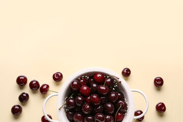 Colander with sweet cherries on beige background