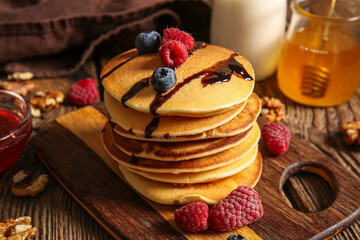 Board of tasty pancakes with raspberries and blueberries on wooden background