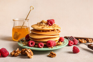 Plate of tasty pancakes with raspberries on light background