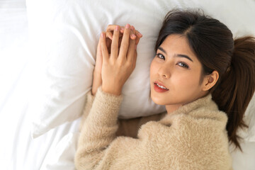 Portrait of smiling cheerful beautiful pretty asian woman clean fresh healthy white skin posing smile in in warm knitted clothes, skincare.Girl felling relax and enjoy time on bed at home.asia beauty