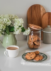 Coffee, cookies with chocolate drops on the kitchen table with a bouquet of hydrangeas