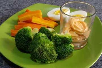 Closeup healthy food on the green plate, with broccoli, carrot, egg, and mayonnaise