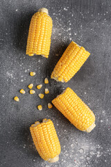 Cut fresh corn cobs and seeds on grey background