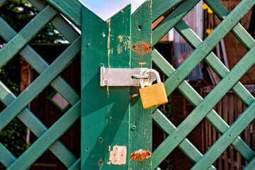 Green gate with padlock and yellow padlock on it in Germany.