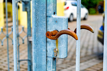 Rusted metal door handle on blue metal pole on sidewalk in Germany.