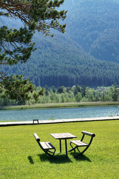 B&auml;nke und Tisch auf einer Wiese vor einem See in den Alpen