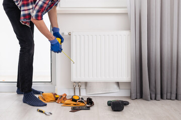 plumber at work. Installing water heating radiator