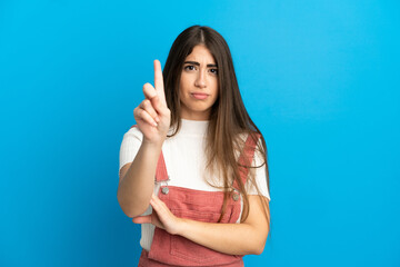Young caucasian woman isolated on blue background counting one with serious expression