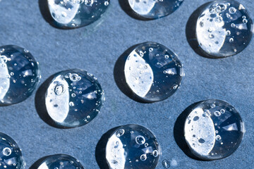 Drops of hyaluronic acid on a dark blue background macro. Sample of cosmetic care product, abstract...
