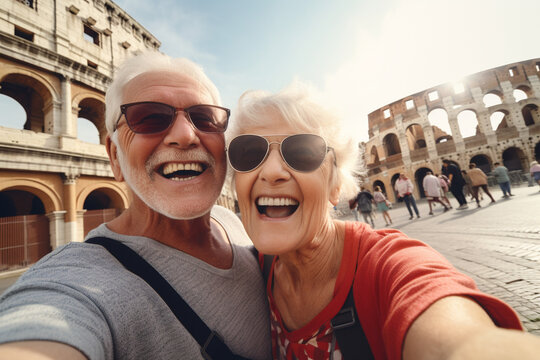 A happy elderly couple of tourists take a selfie in front of the Colosseum. Travel retirement concept. AI generated.