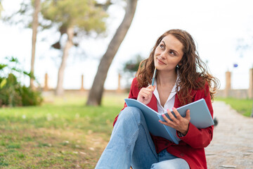 Young caucasian woman at outdoors holding a notebook