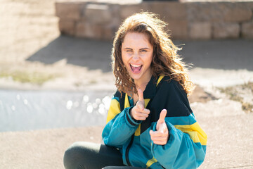 Young sport woman at outdoors pointing to the front and smiling