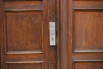 Old, wooden door with a brass door handle outdoors