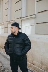 Portrait of a Caucasian man with a puffer jacket and a cap posing outdoors