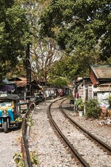 Fototapeta na wymiar A vertical shot of train tracks through a rural area with an outdoor market in Bangkok