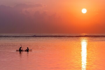 View of a couple leisurely enjoying a paddleboat ride on the beach at sunset
