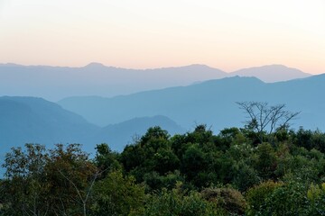 Breathtaking sunset over a rolling landscape of hills and lush green trees in the foreground