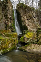 Tranquil landscape featuring a lush green forest with a majestic waterfall cascading over the rocks