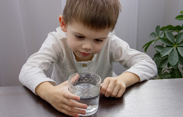 the child looks at the water through a magnifying glass. Selective focus.