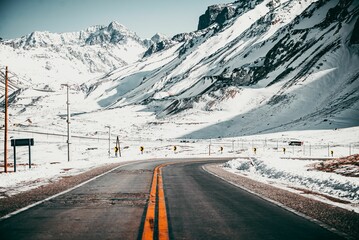 a road in front of some mountains is paved with snow