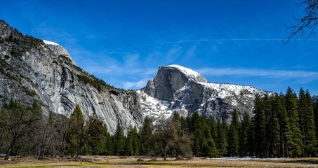 Scenic view of a snowy mountain range covered green forests in Yosemite Park, California