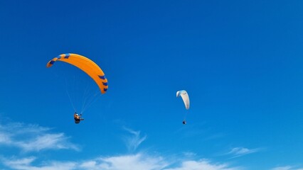 Paragliders soaring in a bright blue sky. Spain.