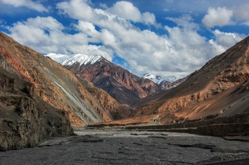 Beautiful landscape with big mountains with snowy peaks against the blue cloudy sky