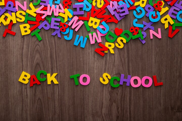 Back to school sign formed from colorful plastic letter on wooden background