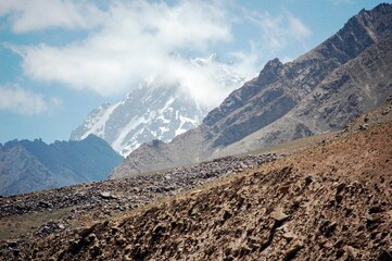 Impressive view of a snow-capped rocky mountain with sparse grasses at its base